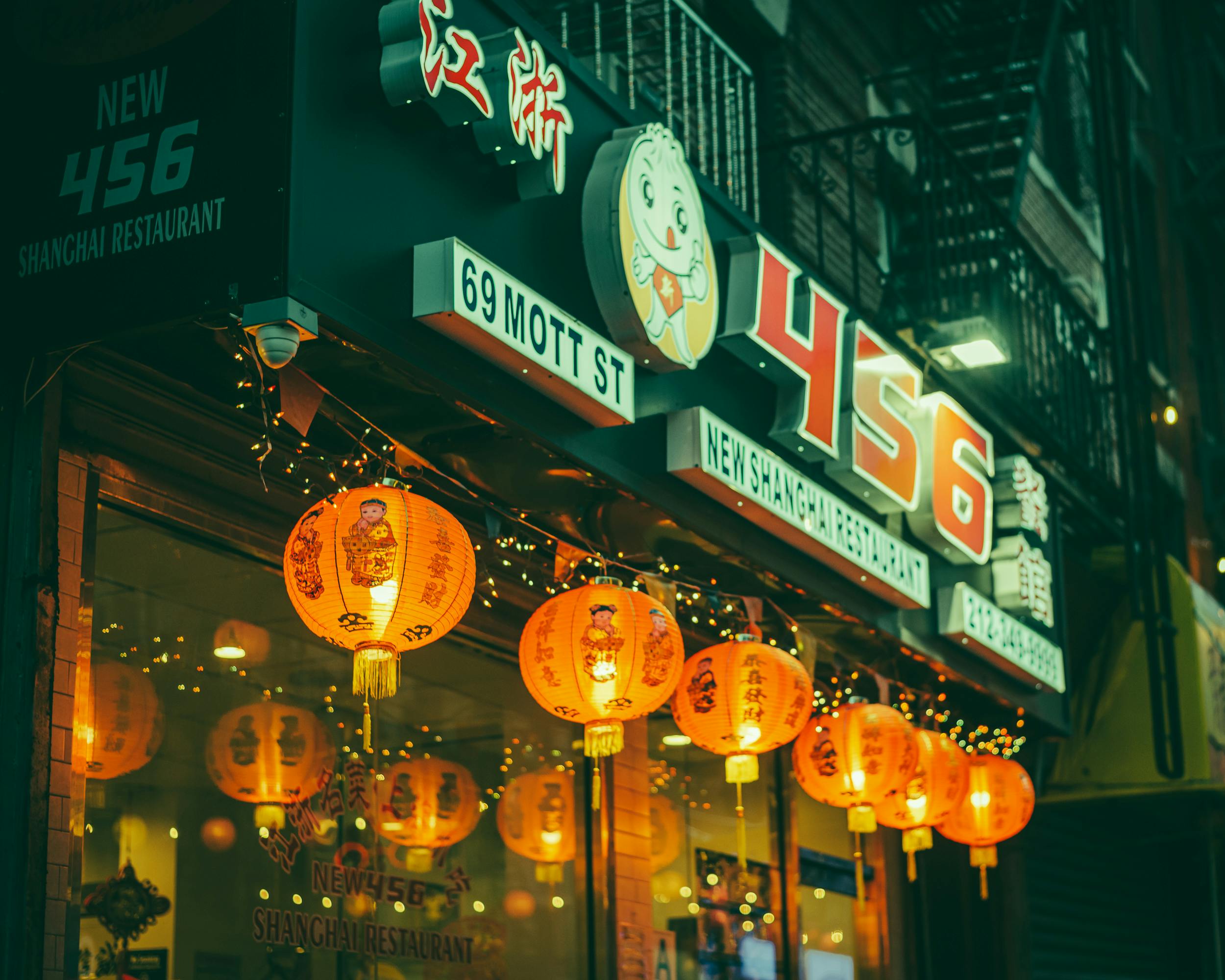 Restaurant exterior at night with illuminated lanterns and storefront signage.